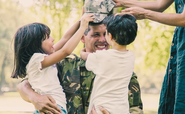 Two Happy Kids Their Mom Meeting Hugging Military Dad Camouflage Uniform Outdoors.jpg